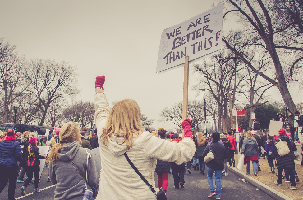 Woman during The Women's March holding a sign that says "we are better than this"